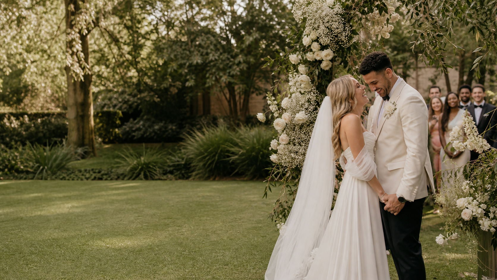 A joyful newly married couple beneath a garden wedding arbour